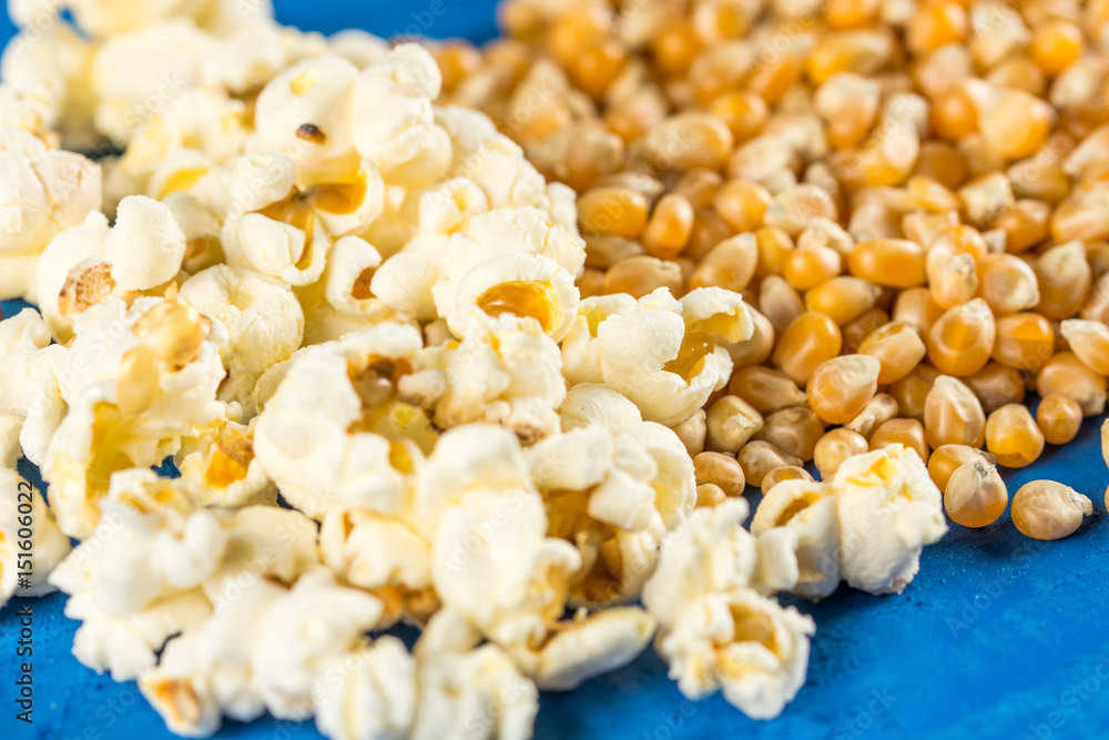 Closeup macro above flat lay raw and fresh popcorns on the blue background