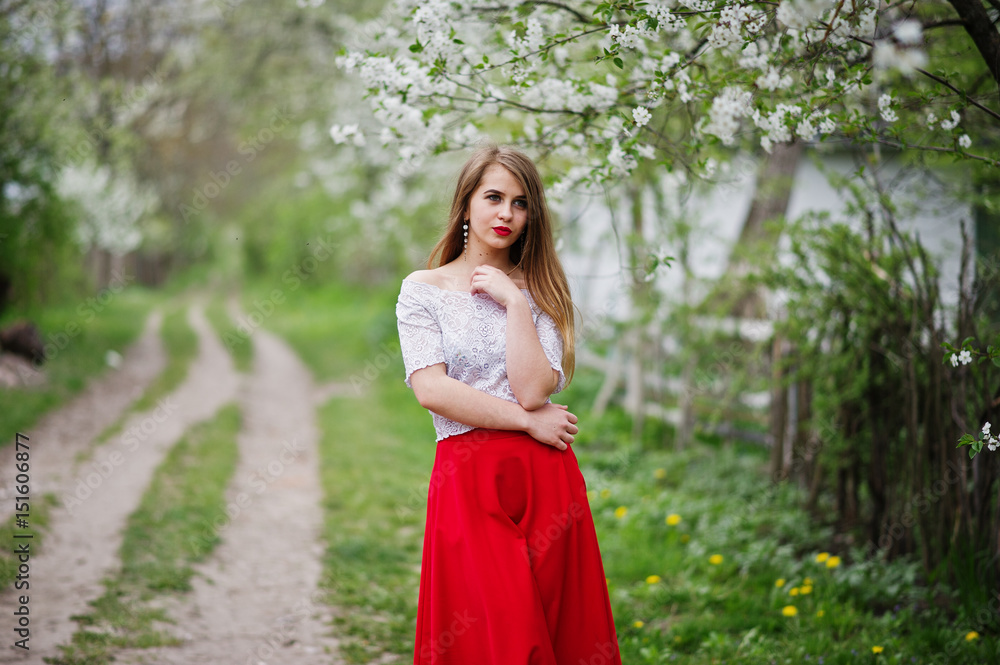 Portrait of beautiful girl with red lips at spring blossom garden, wear on red dress and white blouse.