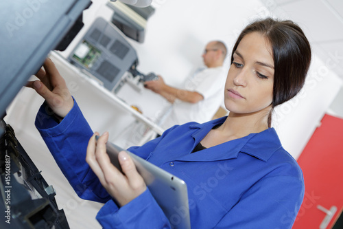 Woman working on electrical appliance, looking at tablet