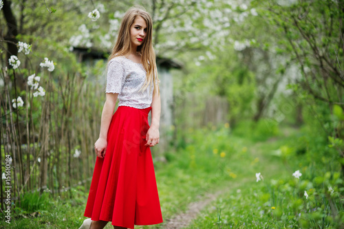 Portrait of beautiful girl with red lips at spring blossom garden, wear on red dress and white blouse. © AS Photo Family