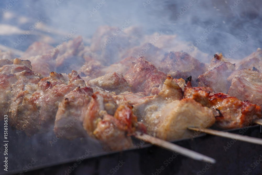 Cooking. Pork meat roasted on a spit. Meat is watered with water, creating splashes and steam. Closeup. When the aperture is wide open, selective focus. Cooking. Pork meat roasted on a spit. Meat is watered with water, creating splashes and steam. Closeup. When the aperture is wide open, selective focus.