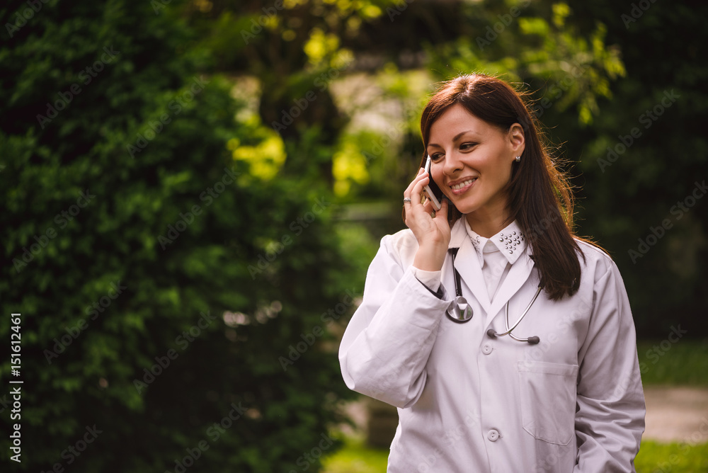Portrait of young smiling confident female doctor talking on phone Portrait of young smiling confident female doctor talking on phone