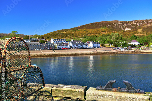 Quay with fish traps and bollard in the foreground and waterfront houses in the background photo