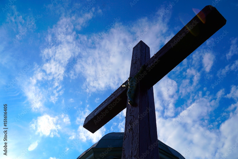 old cross with crucified Jesus Christ against a background of blue sky old cross with crucified Jesus Christ against a background of blue sky