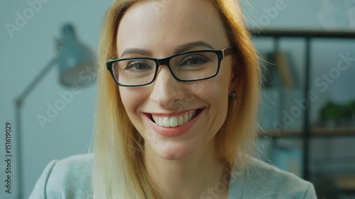 Portrait of young attractive business woman in glasses posing and smiling on camera in office. Close up. photo