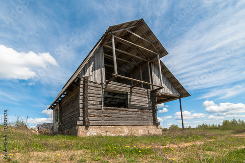 Old abandoned unfinished wooden house against a beautiful blue sky © gluuker