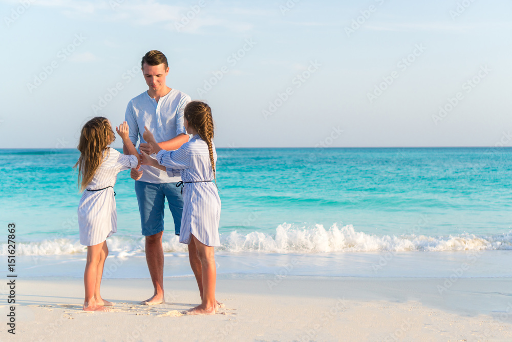 Happy father and his adorable little daughters on the beach Happy father and his adorable little daughters on the beach