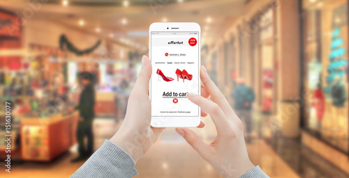 Girl buying red shoes online with modern phone. Blured store in background