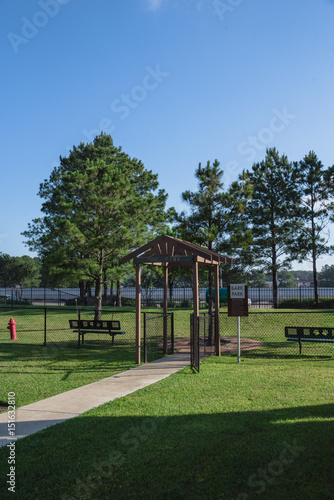 Community on-site dog park at the grassy backyard of a typical apartment complex building in suburban area at Humble, Texas, US. Off-leash dog park with pet stations, toys and bag dispensers