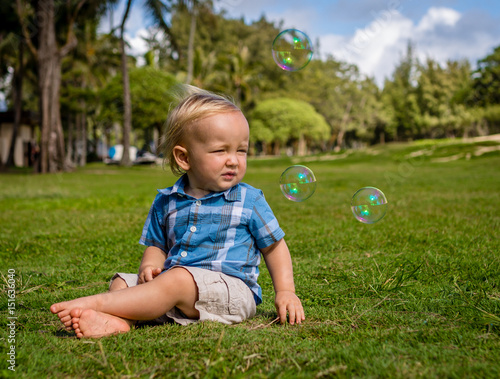 Cute Adorable Toddler Fascinated by Bubbles While Sitting in the Park