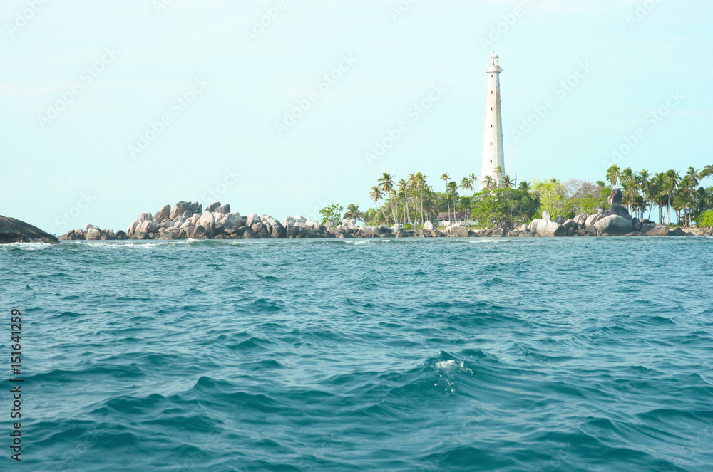White lighthouse standing on an island in Belitung at daytime with no people around. White lighthouse standing on an island in Belitung at daytime with no people around.