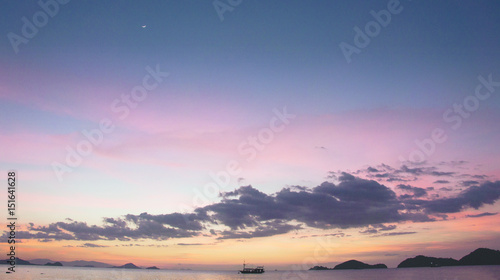 Boat silhouette crossing the ocean at nightfall with orange violet purple blue colored sunset sky on the horizon  Labuan Bajo Bajawa.