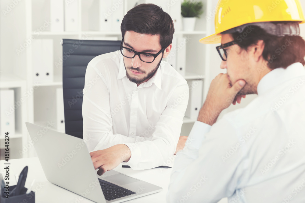 Two engineers discussing project in office Two engineers discussing project in office