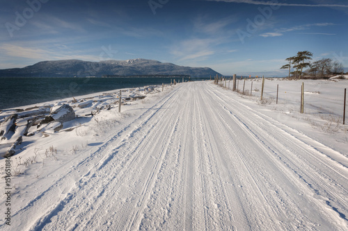 Snow Covered Country Road. Snow covers a road in the San Juan Islands of Washington State with Orcas Island in the background.