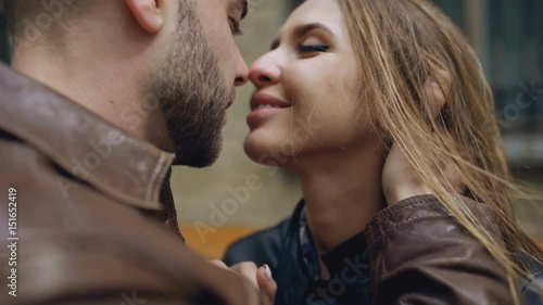 Closeup of happy loving couple kissing and embracing while havinhg walk in city street photo