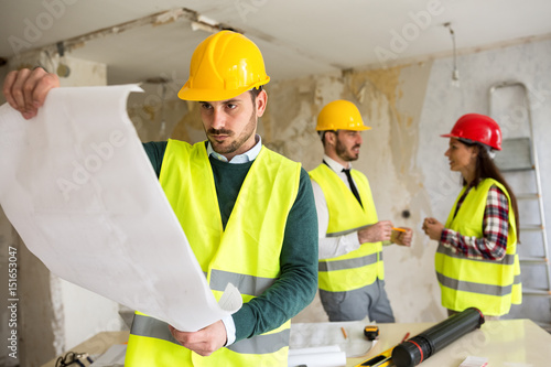 Young architect checking blueprint of building reconstruction