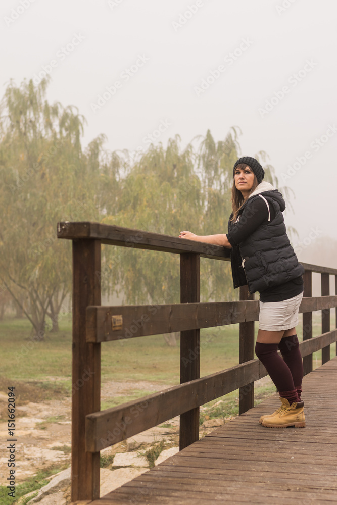 Mujer joven posando en el parque con niebla en invierno