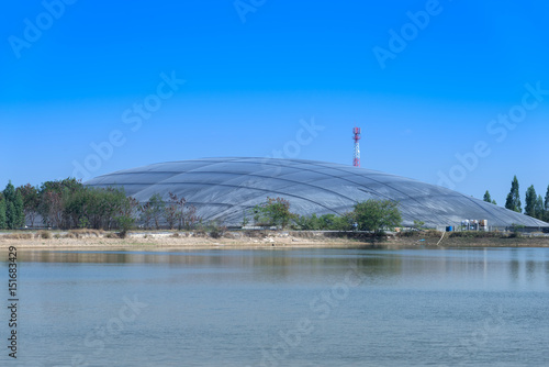 plastic cover of storage facility and production of bio gas from sugar cane oil refinery plant with surface of pond in foreground