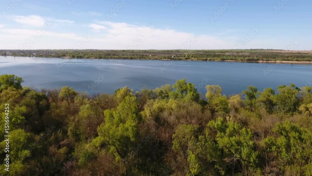 Impressive aerial view on the sparkling blue waters of the Dnipro river and its picturesque riverbank in a sunny day in spring. The skyscape and horizon look great and gorgeous. Impressive aerial view on the sparkling blue waters of the Dnipro river and its picturesque riverbank in a sunny day in spring. The skyscape and horizon look great and gorgeous.