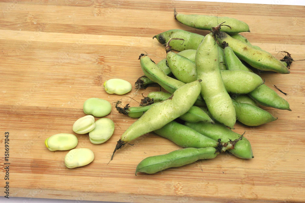 fresh broad beans on bamboo cutting board fresh broad beans on bamboo cutting board