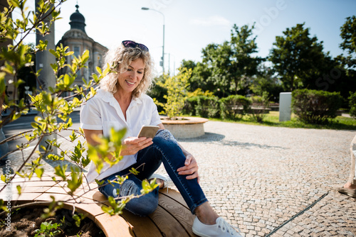 Woman texting on the smartphone sitting in a park