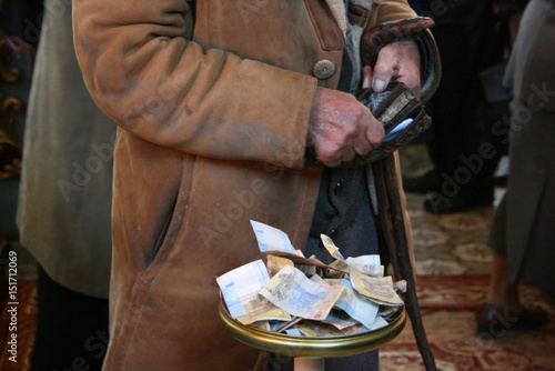 Hands of old man with a wallet at the plate to raise money in the Orthodox Church photo