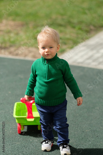 One year old baby boy toddler wearing green sweater at playground
