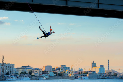 young beautiful brave woman roupejumping in the evening on the bridge