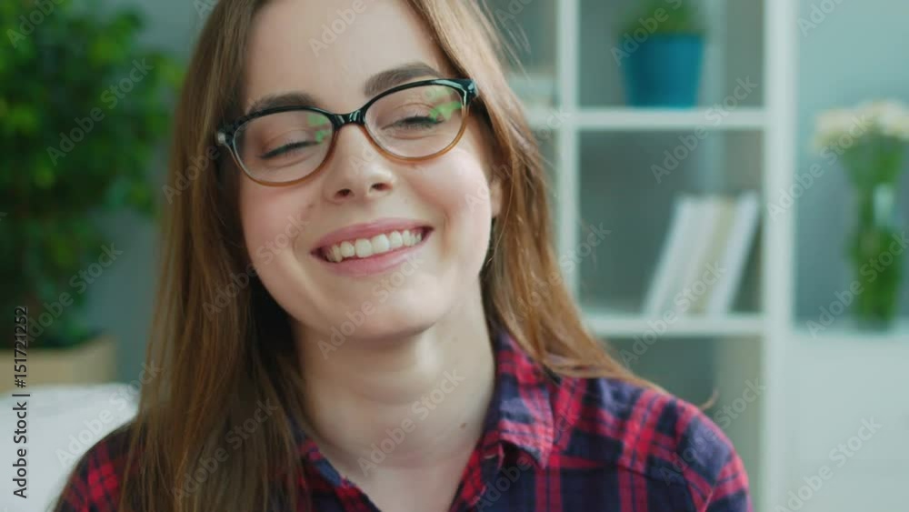 Portrait of beatiful emotional young woman with glasses smiling on the camera in the living room. Close up. Portrait of beatiful emotional young woman with glasses smiling on the camera in the living room. Close up.