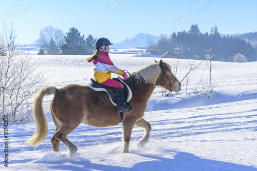 kleine Reiterin beim Ausritt im Schnee