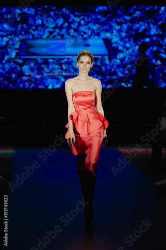 Beautiful fashion model in red dress walking on runway