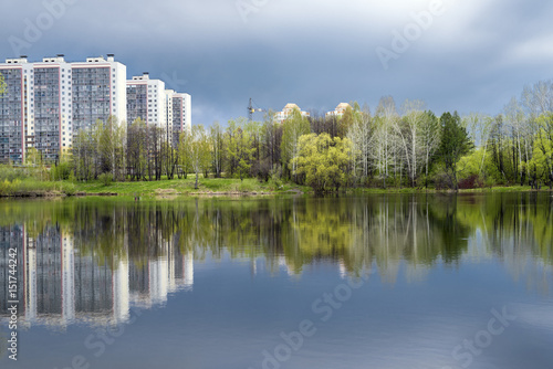 Grove and houses are reflected in the lake water