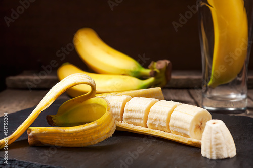 Bundle of bananas and a sliced banana on vintage wooden background, selective focus