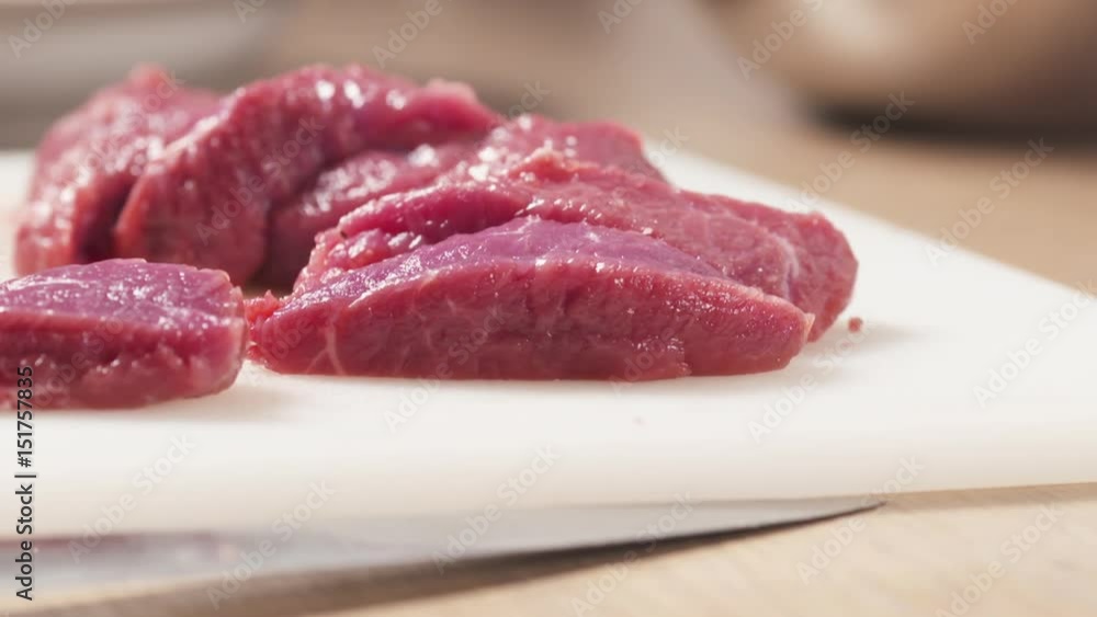 Slow motion slide shot of raw beef with a knife on plastic board, 180fps prores footage Slow motion slide shot of raw beef with a knife on plastic board, 180fps prores footage
