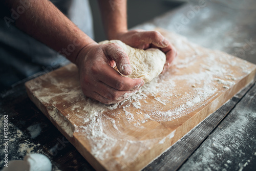 Baker hands kneading the dough with flour
