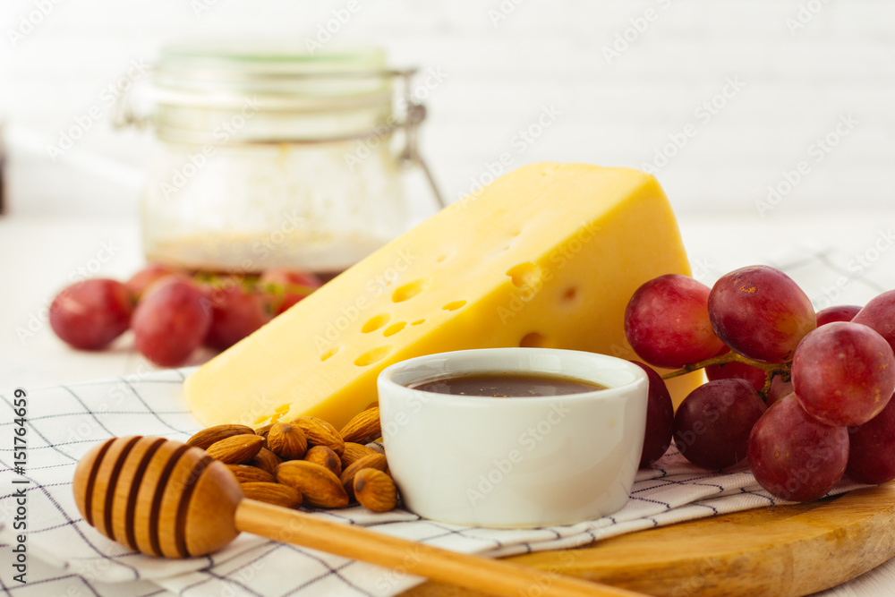 Cheese, almond, grapes and honey on wooden plate Cheese, almond, grapes and honey on wooden plate