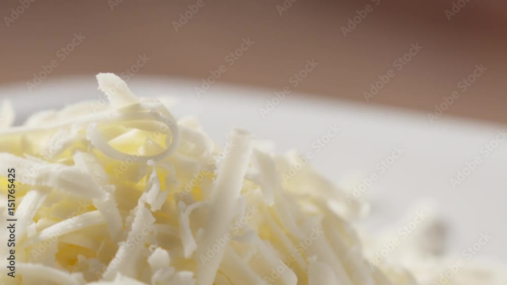 Slow motion slide shot of grated pizza mozzarella cheese falls in plate, 180fps prores footage