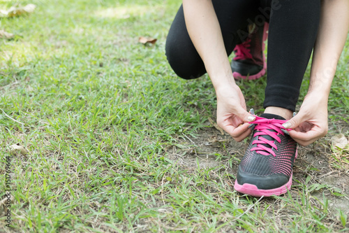 Urban athlete woman tying running shoe laces. Female sport fitness runner getting ready for jogging outdoors on forest path in city park © 88studio