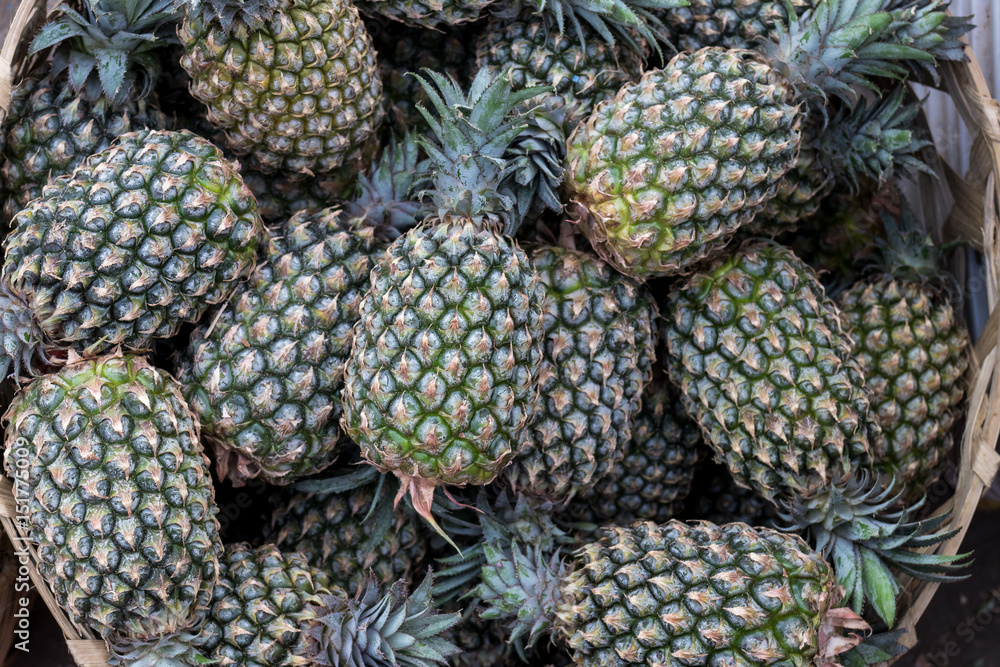 Pile of tropical organic pineapples fruits in basket for sell in tradtional farmer market of Bali island, Indonesia. Pile of tropical organic pineapples fruits in basket for sell in tradtional farmer market of Bali island, Indonesia.