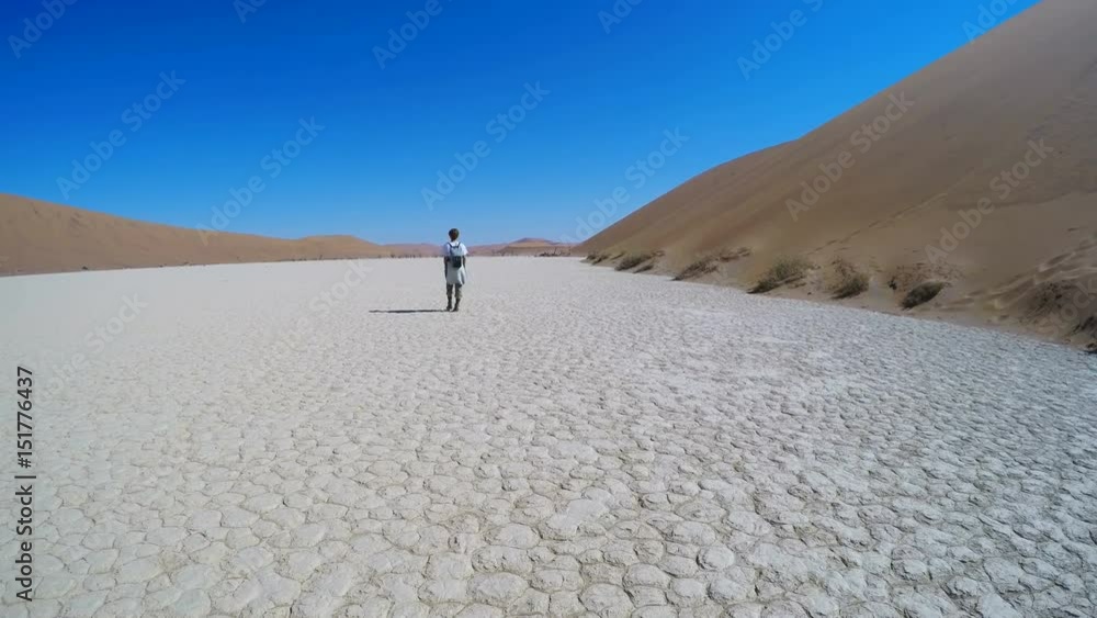 Tourist walking on the scenic dunes of Sossusvlei, Namib desert, Namib Naukluft National Park, Namibia. Afternoon light. Adventure and exploration in Africa. Tourist walking on the scenic dunes of Sossusvlei, Namib desert, Namib Naukluft National Park, Namibia. Afternoon light. Adventure and exploration in Africa.