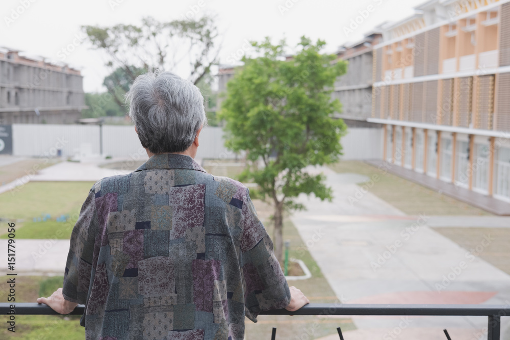 Senior elder standing on balcony looking at the city view, elderly asian woman enjoying nice weather on terrace Senior elder standing on balcony looking at the city view, elderly asian woman enjoying nice weather on terrace