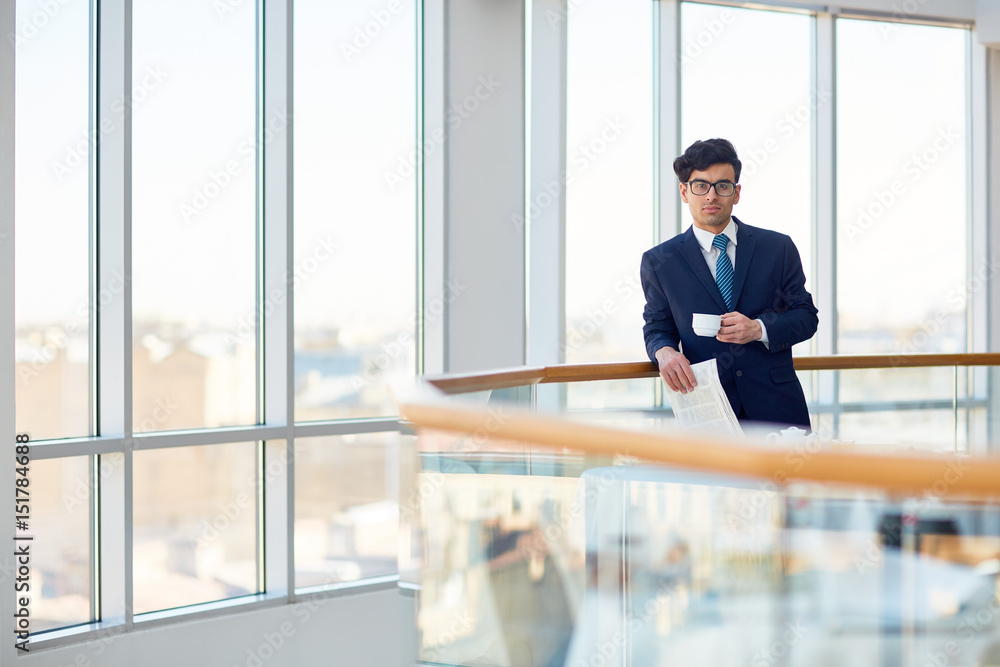Serious employer with cup of coffee and newspaper Serious employer with cup of coffee and newspaper