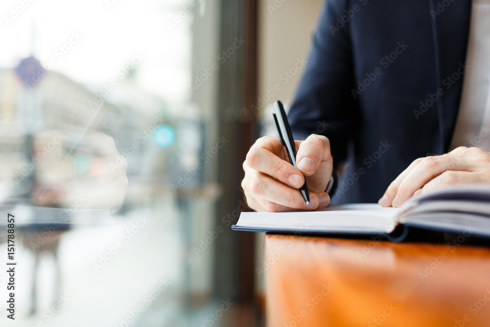 Closeup shot of unrecognizable businessman wearing formal suit making notes in planner scheduling for day Closeup shot of unrecognizable businessman wearing formal suit making notes in planner scheduling for day