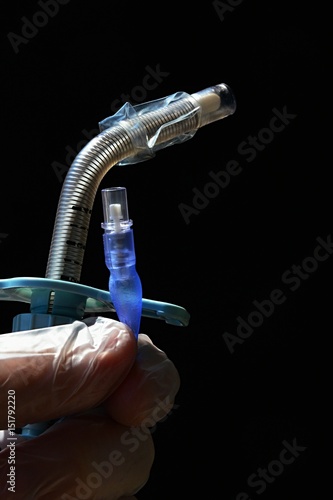 Renforced tracheostomy cannula with deflated polyurethane cuff on dark background photo