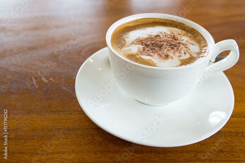 A cup of cappuccino coffee on wooden table
