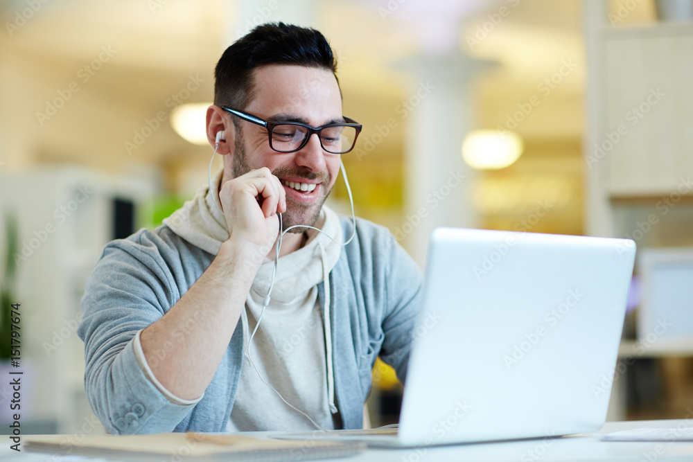 Businessman with earphones enjoying break in front of laptop Businessman with earphones enjoying break in front of laptop