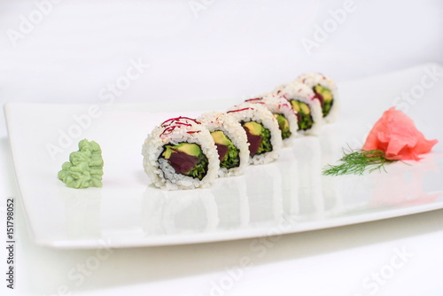 Rolls and sushi served with wasabi and ginger on a white plate