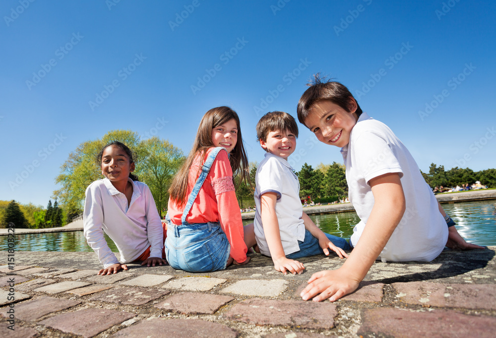 Four kids sitting on embankment during summer time Four kids sitting on embankment during summer time