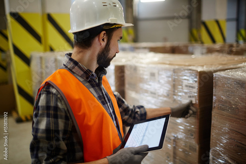 Dispatcher in uniform and helmet checking barcodes on packages photo