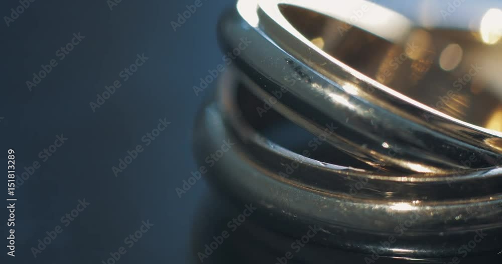 Extreme close up macro shot of two gold wedding rings lying on dark surface shining with light. Transfusion of light on rings. Extreme close up macro shot of two gold wedding rings lying on dark surface shining with light. Transfusion of light on rings.